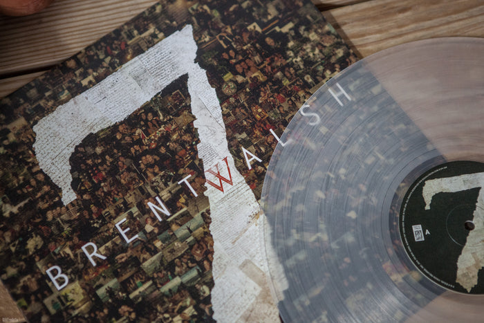 A close-up of the translucent Crystal Clear LP by Brent Walsh partially covers its album cover, which features “Brent Walsh” and a mosaic-filled number seven. This Limited Pressing showcases intricate photo mosaics on the cover.