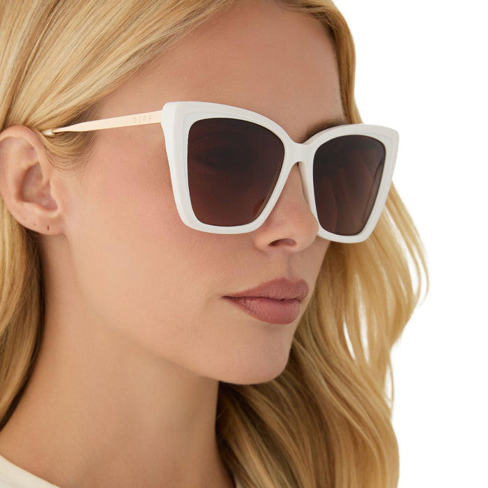 on model - blonde female wearing diff eyewear featuring the becky ii cat eye sunglasses with a snowbound white frame and brown gradient lenses angled view