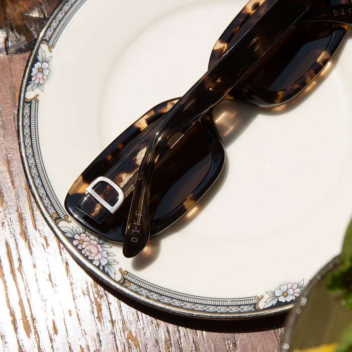 flat lay of daphne espresso tortoise sunglasses laying on a picnic table