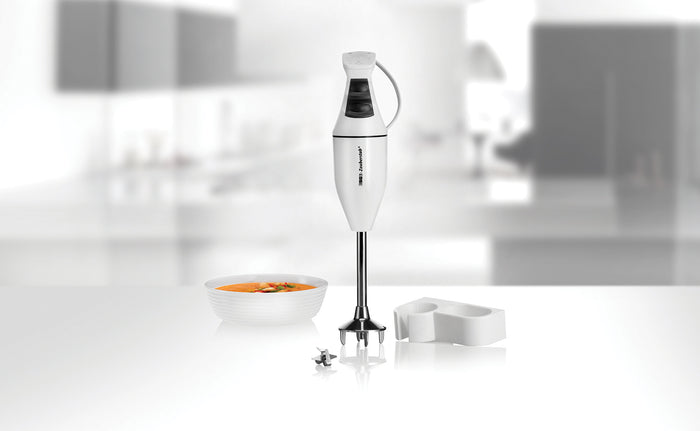 Der ESGE Zauberstab ESGE-Zauberstab 901205 Set M100 Design-Stabmixer steht aufrecht auf einer modernen KΓΌchentheke neben einer SchΓΌssel Suppe, einem Mixmesser und einem weiΓen Kunststoffaufsatz mit sanft verschwommenem Hintergrund.