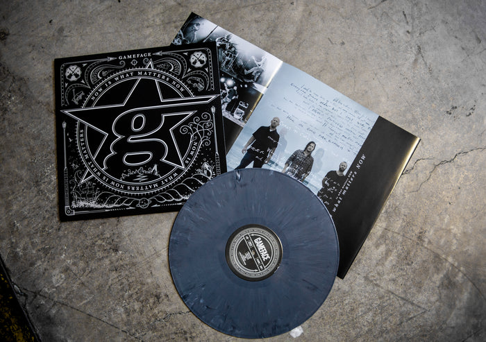 A Grey Marble vinyl record by Gameface rests on concrete beside its black and white album cover and an open booklet with band photos and notes—a Limited Pressing from Gameface.
