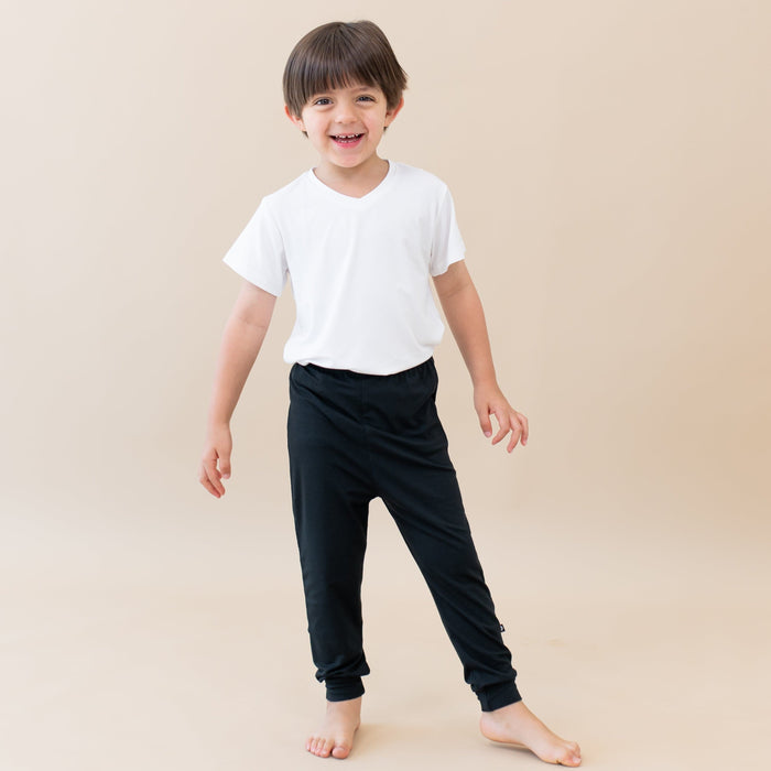 Smiling toddler standing while wearing Kyte Baby Pants in Midnight and V Neck in Cloud
