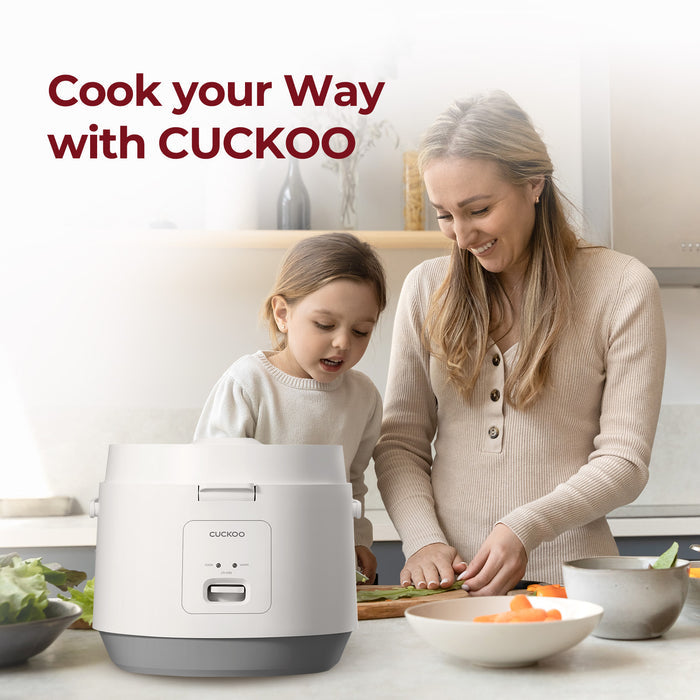 Cook your way with CUCKOO: A woman and child cooking together in a kitchen next to a white Cuckoo rice cooker. (CR-1095)