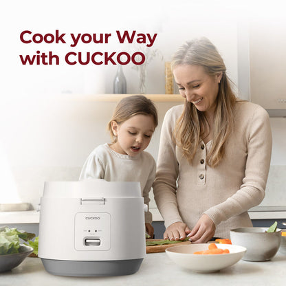 Cook your way with CUCKOO: A woman and child cooking together in a kitchen next to a white Cuckoo rice cooker. (CR-1095)