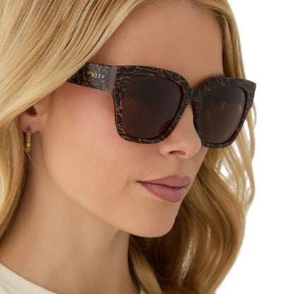 on model - female wearing diff eyewear featuring the bella ii square sunglasses with a animal print frame and brown lenses angled view