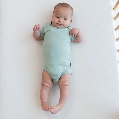 Baby wearing Bodysuit in Sage in a crib