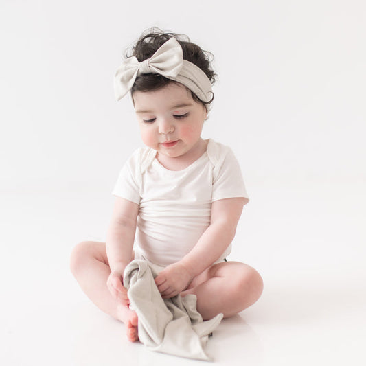 Baby wearing Bow Headband in Oat while holding Kite Lovey