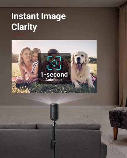 A Capsule Max portable projector sits on top of a stand and projects a family lying in the grass with their dog.