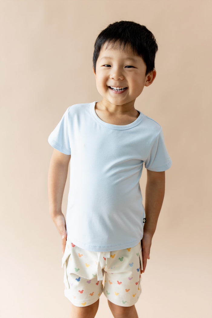 Young boy wearing blue tshirt and cargo shorts with pastel mickey mouse head print