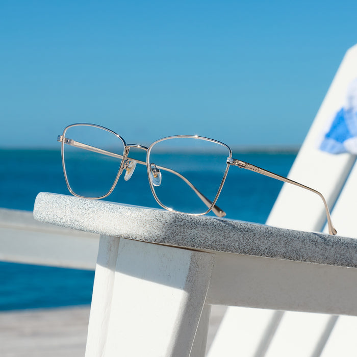 still life - diff eyewear featuring the connie cat eye prescription glasses with a silver frame laying on a chair at the beach