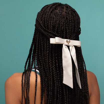 KITSCH Satin Bow Hair Clip - Cream — model wearing the cream satin bow clip in her hair — metal barrette glides in without snagging — statement accessory for a half-up or ponytail