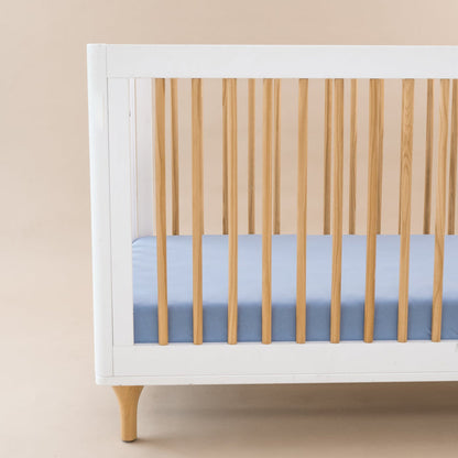Crib Sheet in Slate shown on a mattress in a modern white and wooden crib