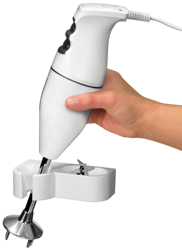 Eine Hand hält den ESGE-Zauberstab 901205 Set M100 Design-Stabmixer von ESGE Zauberstab und stellt ihn in seinen weißen Ständer, wobei der Metallklingenaufsatz sichtbar ist.