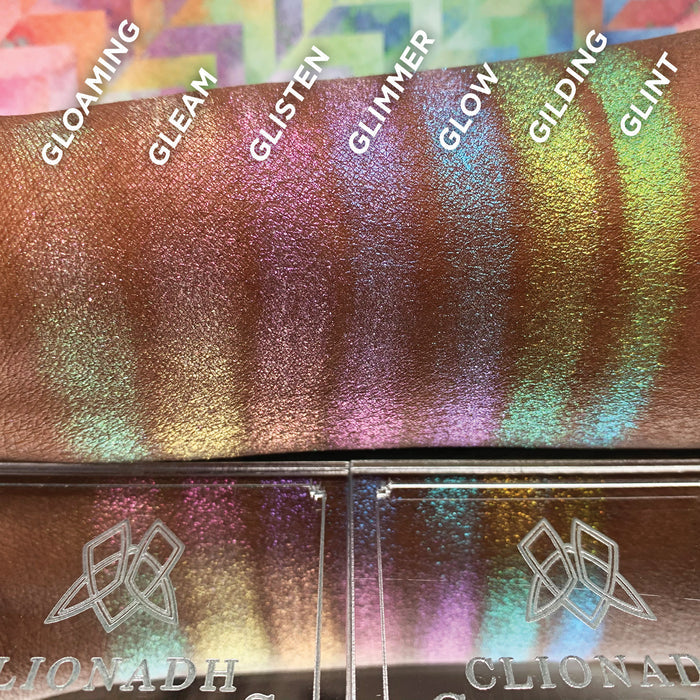 Straight angled arm swatches on deep skin tone of Gilding Glitter-Type Iridescent Multichrome Eyeshadow compared to Gloaming, Gleam, Glisten, Glimmer, Glow, Glint