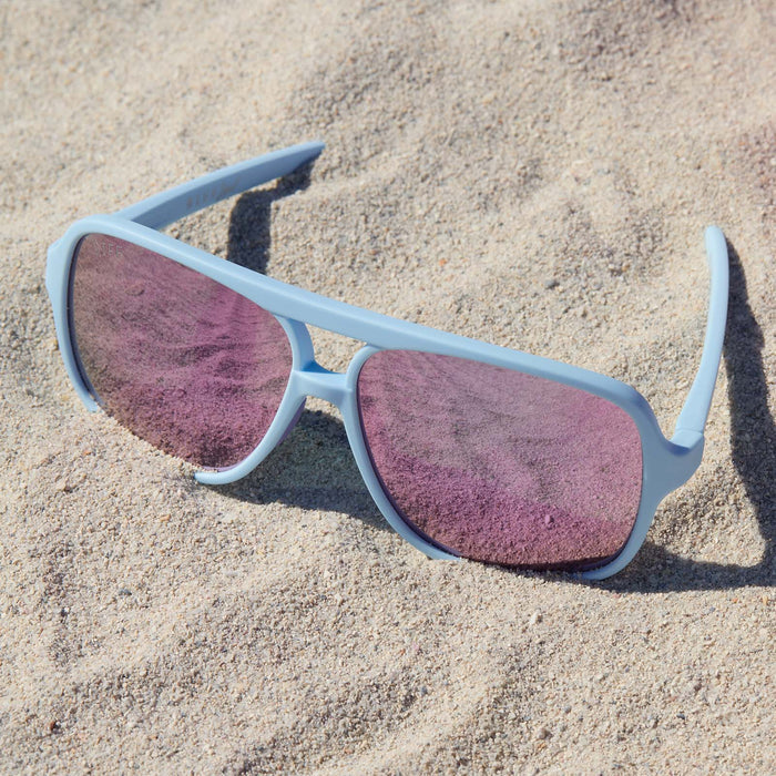 lifestyle - still life of diff eyewear hangtime aviator sport sunglasses in baby blue laying in the sand on the beach