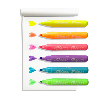 White sketchbook with row of uncapped OOLY Heart Pops Neon Highlighters with heart swatches on white background