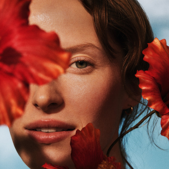 Close up of model's face with hibiscus flowers in frame