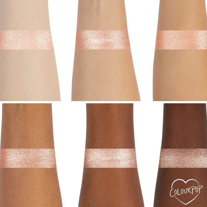 ColourPop I Heart This Super Shock Shadow swatch shows a wide shimmery champagne band across six arms from light to deep skin tones, highlighting even payoff and sparkle, with a small ColourPop heart logo in the corner.