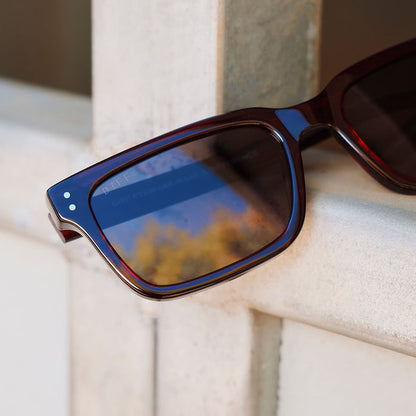 still life of yellowstone x diff eyewear john dutton rectangular sunglasses with a redwood frame and grey polarized lenses front view