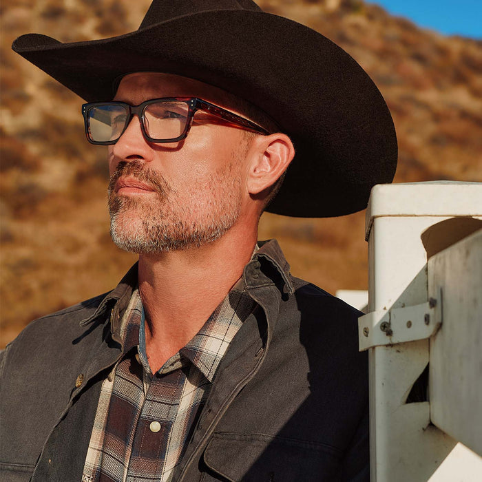 lifestyle - male with cowboy hat wearing yellowstone x diff eyewear featuring the john dutton rectangle prescription glasses with a sequoia tortoise frame angled view