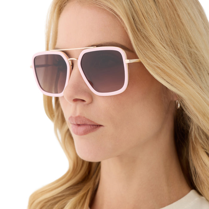 on model - female wearing diff eyewear featuring the jordan navigator sunglasses with a powder pink with gold frame and brown gradient lenses angled view
