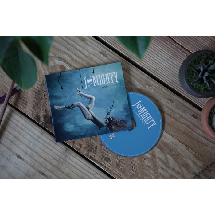 An I The Mighty CD and its case sit on a wooden table near a potted succulent and leafy plant. The EP’s cover shows a person floating underwater, reflecting the ethereal mood of I The Mighty’s music.