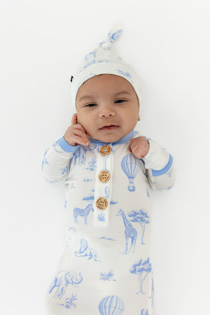 Close up of infant wearing the Knotted Gown with Hat Set in Toile Safari showing the Kyte Baby engraved wooden buttons