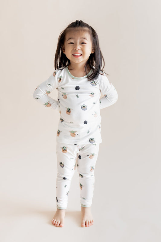 Girl smiling in Long Sleeve Pajamas in Grogu™ print on a cream background
