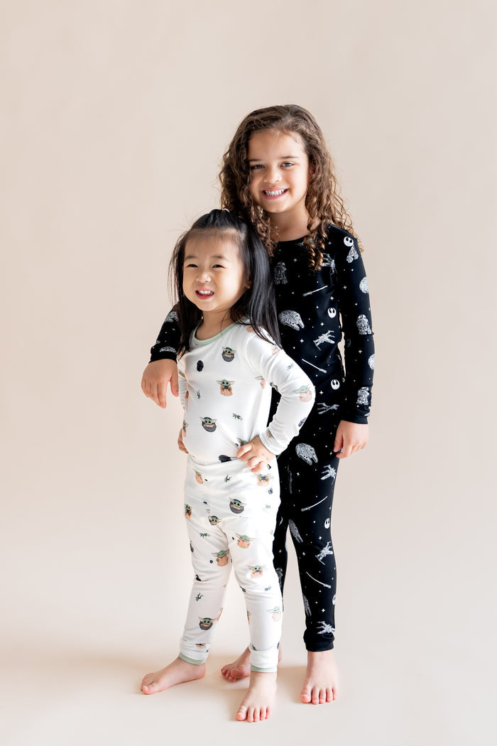 Two girls posing in Long Sleeve Pajamas in in STAR WARS™ and Grogu™ print on a cream background