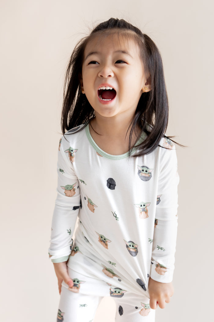 Girl wearing Long Sleeve Pajamas in Grogu™ print on a cream background