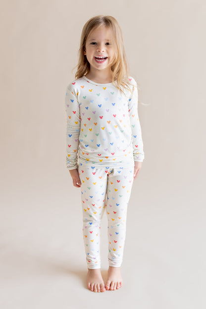 Girl smiling in Long Sleeve Pajamas in Pastel Mickey Mouse print on a cream background