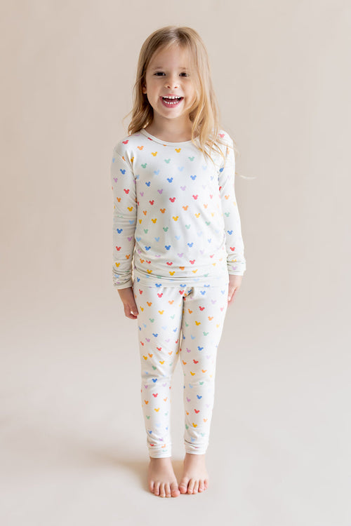 Girl smiling in Long Sleeve Pajamas in Pastel Mickey Mouse print on a cream background