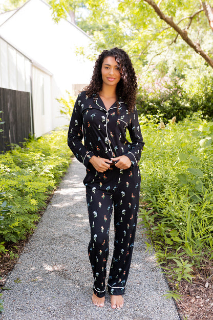 Model wearing Long-Sleeved Women's Pajama Set in Midnight Wildflower print standing outdoors surrounded by trees