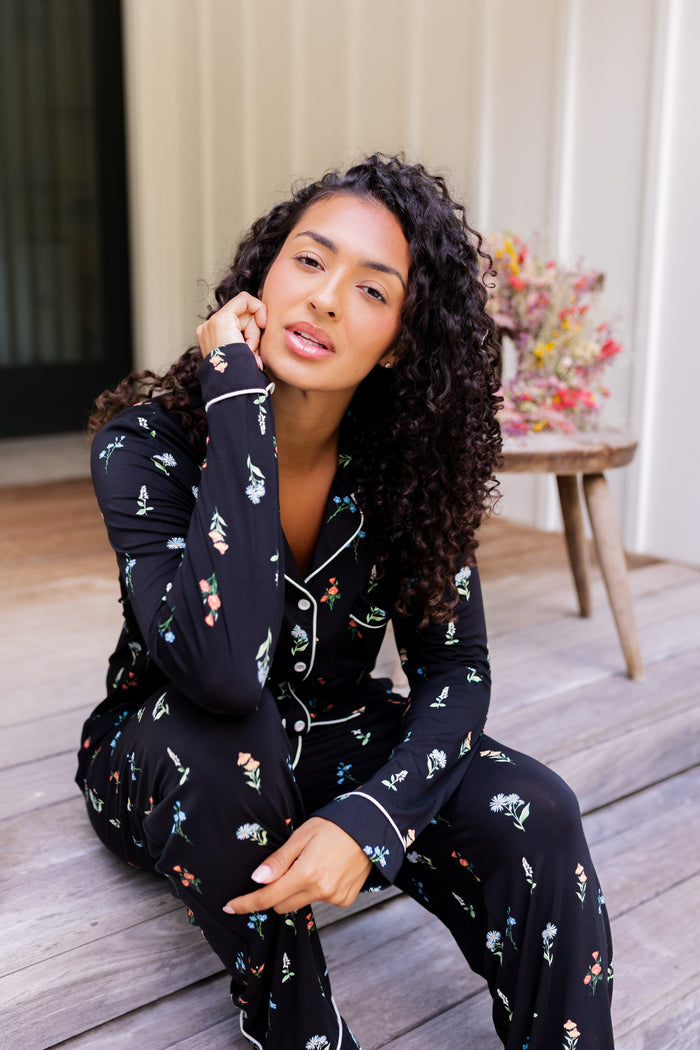 Model sitting outdoors on steps wearing Long-Sleeved Women's Pajama Set in Midnight Wildflower print