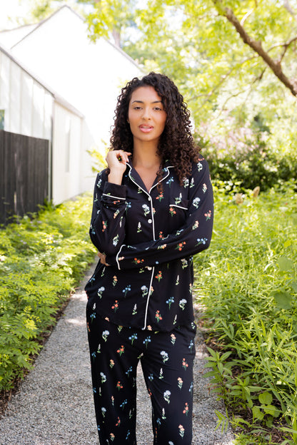 Model standing outdoors surrounded by trees in Long-Sleeved Women's Pajama Set in Midnight Wildflower print