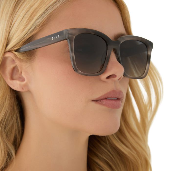 on model - blonde female wearing diff eyewear featuring the meredith square sunglasses with a smoke marble frame and grey gradient polarized lenses angled view