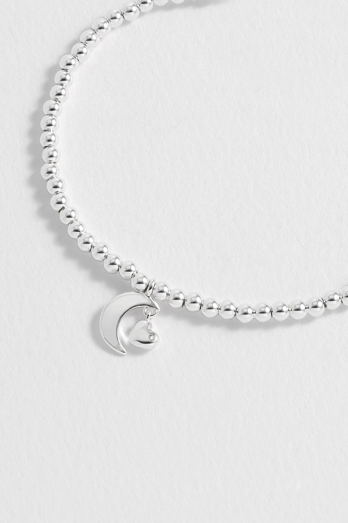 Silver bracelet with a moon charm on a light gray background