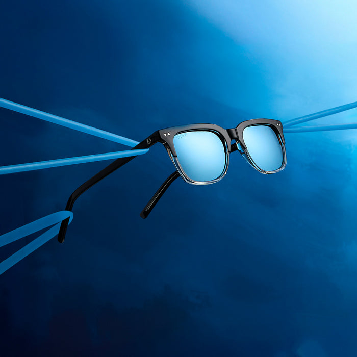 lifestyle - marvel fantastic four x diff eyewear featuring the mr. fantastic square sunglasses with a black to clear frame and quantum blue mirror polarized lenses angled view