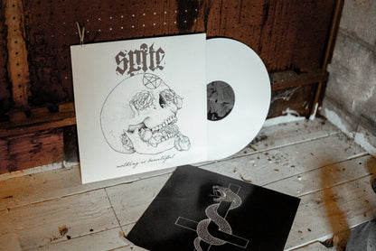 A white jacket shows a skull with roses coming out of its mouth and eyes with the words "nothing is beautiful" at the bottom. "Spite" with a skull as the dot of the "i" is at the top. A white vinyl peeks out of the jacket. The jacket and vinyl rests against a broken down door and floorboard.