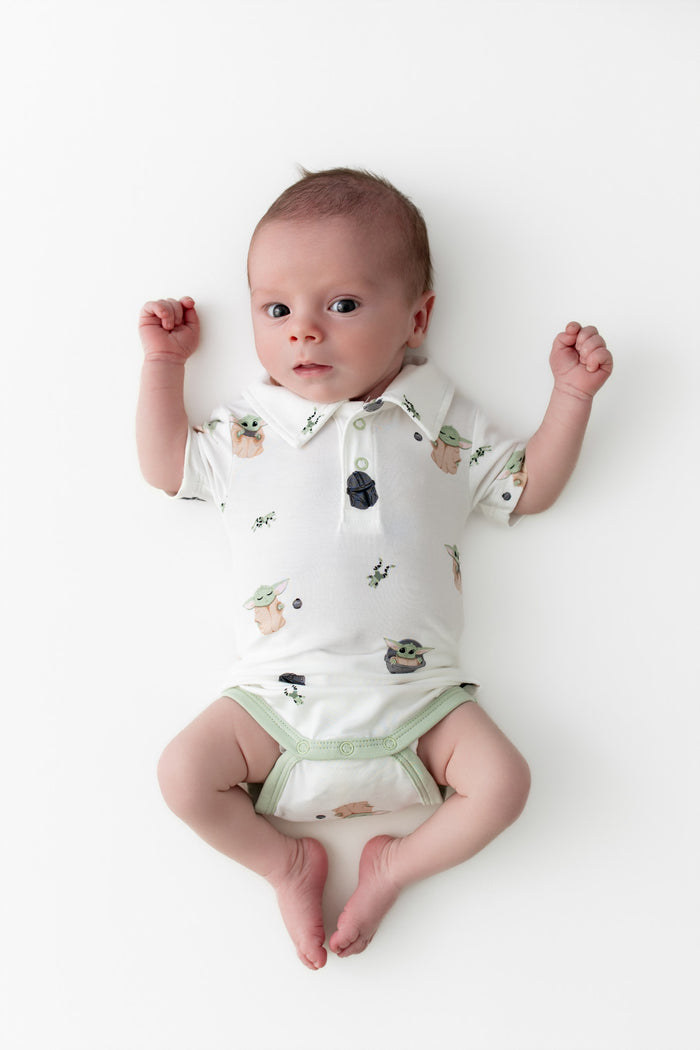 Newborn laying on a white surface wearing the Polo Bodysuit in Grogu™