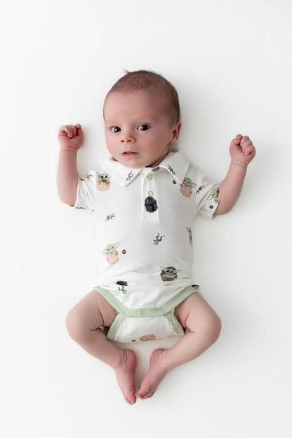 Newborn laying on a white surface wearing the Polo Bodysuit in Grogu™