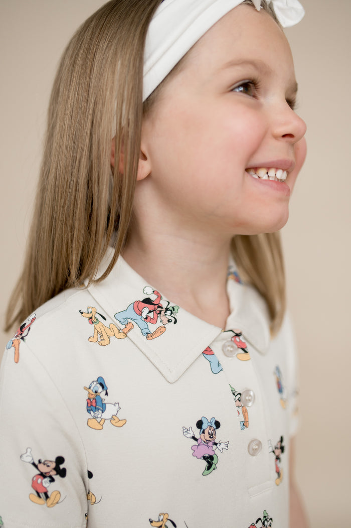 Young girl wearing a dress with cartoon character prints on a beige background