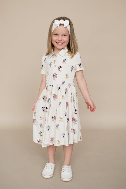 Young girl wearing a mickey character dress on a beige background