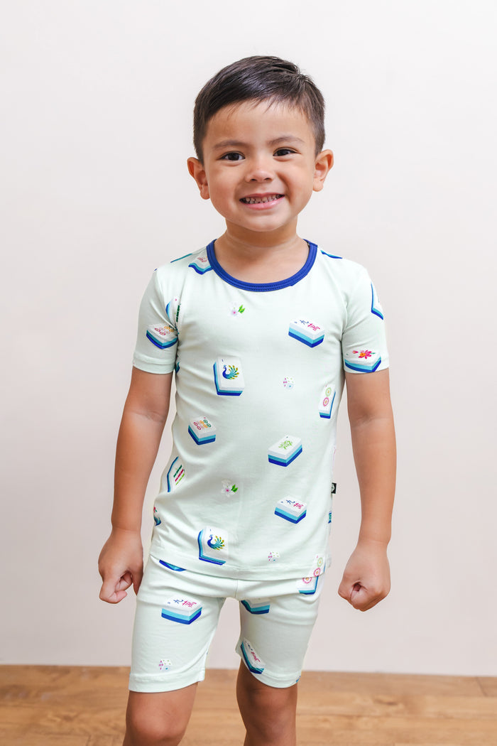 Boy posing in Short Sleeve Pajamas in Dew Mahjong print against a beige background