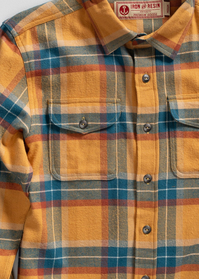 Yellow, blue, and red plaid flannel shirt with buttoned pockets, labeled "Iron and Resin Premium Goods," medium size.
