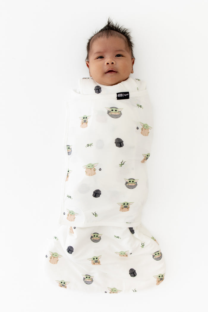 Newborn laying on a white surface swaddled in the Sleep Bag Swaddler in Grogu™ 1.0