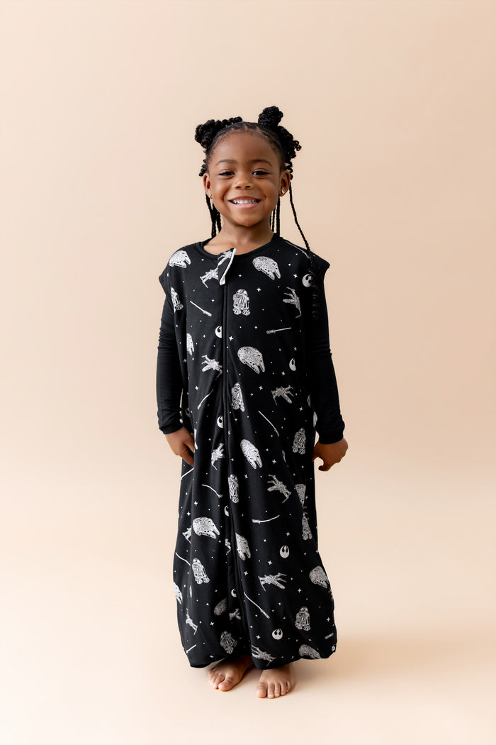 Smiling girl wearing the Sleep Bag Walker in STAR WARS™ 1.0 with long sleeve black pajamas on underneath