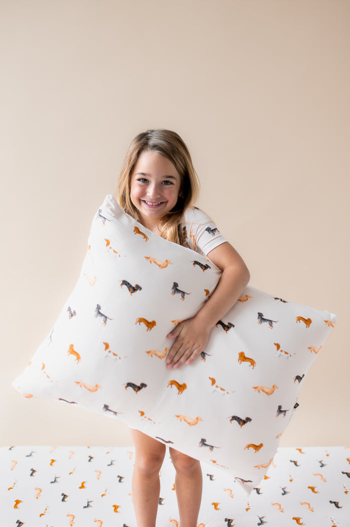 Girl holding Standard Pillowcase in Dachshund print on a beige background