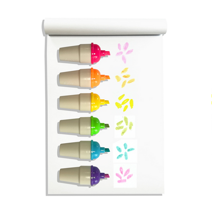 Row of uncapped OOLY Sweet Scoops Scented Neon Highlighters on a white sketchbook with colored swatches