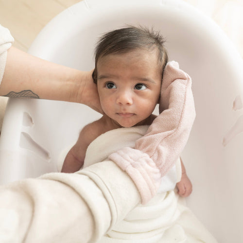 Parent using Blush Pink Terry Bath Mitt for newborn bath